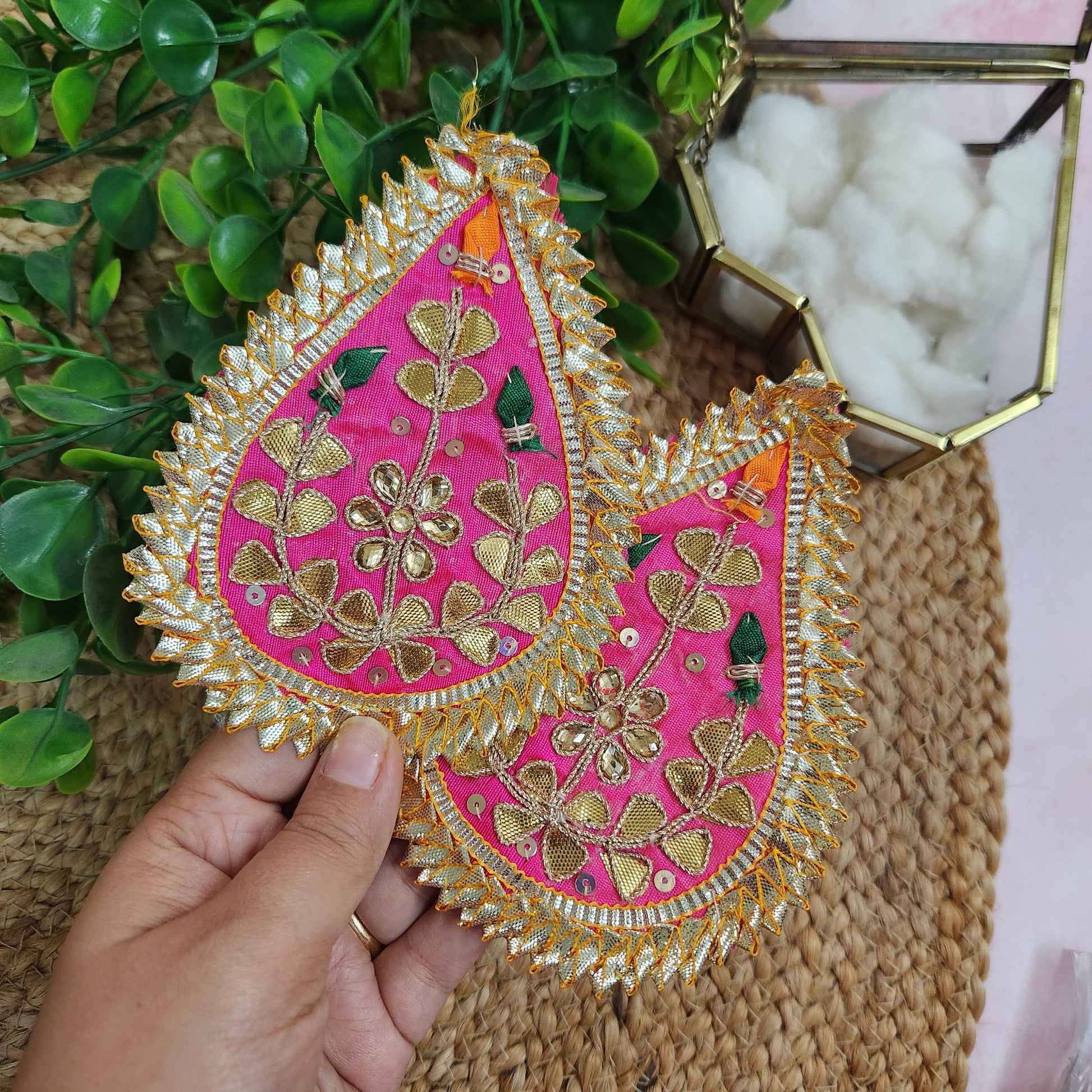 Decorative pink and gold heart-shaped item held by a hand with a natural background